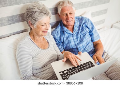 Senior couple using laptop in bedroom - Powered by Shutterstock