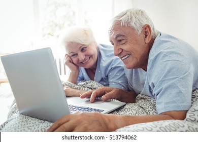 Senior couple using laptop in bedroom - Powered by Shutterstock