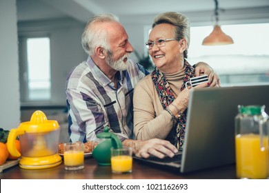 Senior couple using the laptop together at home in the kitchen - Powered by Shutterstock