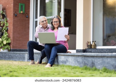 Senior couple using laptop together at home backyard - Powered by Shutterstock