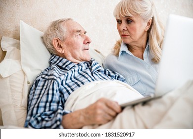 Senior couple using laptop while sitting on the bed. They are seriously discussing something - Powered by Shutterstock