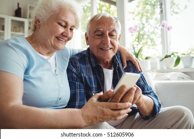 Senior Couple Using Mobile Phone At Home