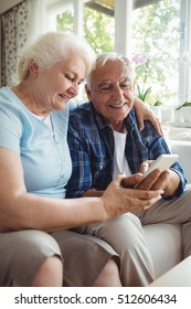 Senior Couple Using Mobile Phone At Home