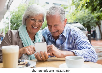 Senior couple using mobile phone in outdoor cafe - Powered by Shutterstock