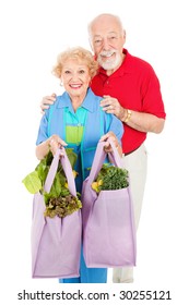 Senior Couple Using Reusable Shopping Bags To Bring Home Their Groceries.  Isolated On White.