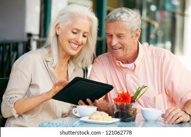 Senior Couple Using Tablet Computer At Outdoor Cafe - Powered by Shutterstock