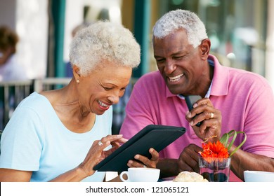 Senior Couple Using Tablet Computer At Outdoor Cafe - Powered by Shutterstock