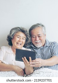 Senior Couple Using A Tablet Phone Computer Face Time Call To Relatives Descendant Relatives Grandchild, Smiling Feel Happy In Sofa At Home - Lifestyle Senior Concept