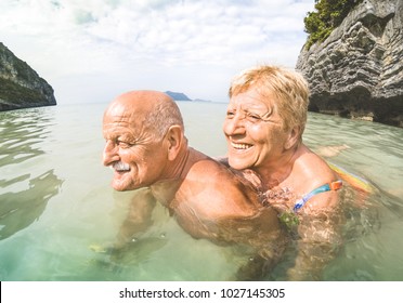 Senior couple vacationer having genuine playful fun on tropical beach in Thailand - Snorkel tour in exotic scenario - Active elderly and travel concept around the world - Warm afternoon bright filter - Powered by Shutterstock