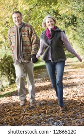 Senior Couple Walking Along Path In Autumn Woods