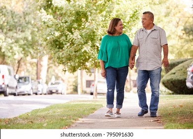 Senior Couple Walking Along Suburban Street Holding Hands - Powered by Shutterstock