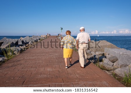 Senior couple walking by the sea, aged people with a healthy lifestyle, long lasting couple holding hands, life expectancy is high in Spain. Mediterranean inspiration, Spain