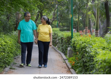 A SENIOR COUPLE WALKING HAND IN HAND IN A PARK - Powered by Shutterstock