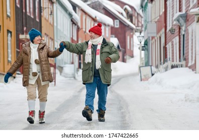 雪の多い通りを手に手に手に手に手を取って歩く老夫婦がの写真素材