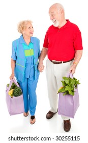 Senior Couple Walking Home With Their Groceries In Reusable Shopping Bags.  Isolated On White.