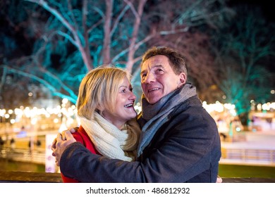 Senior Couple Walking In Night City. Winter, Historical Building