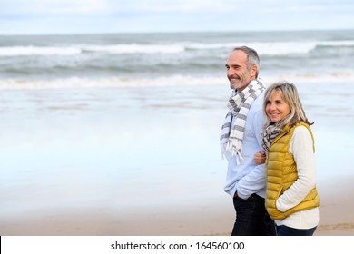 Senior couple walking on the beach in winter time
