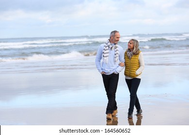 Senior Couple Walking On The Beach In Winter Time