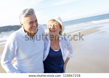 Senior couple walking on the beach in fall season