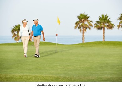 Senior couple walking on golf course - Powered by Shutterstock