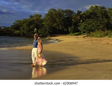 senior couple walking on a maui beach at sunset