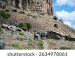 Senior couple walking on a trail at the base of the rocky cliffs of the Clarno Palisades in John Day Fossil Beds National Monument, Clarno Unit, central Oregon
