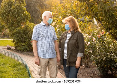 Senior Couple Walking Outside In Nature Wearing Medical Masks