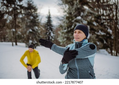 Senior couple warming-up and stretching in snowy forest before winter hike. - Powered by Shutterstock