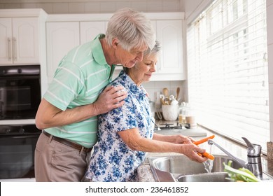 Senior couple washing vegetables at sink at home in the kitchen - Powered by Shutterstock