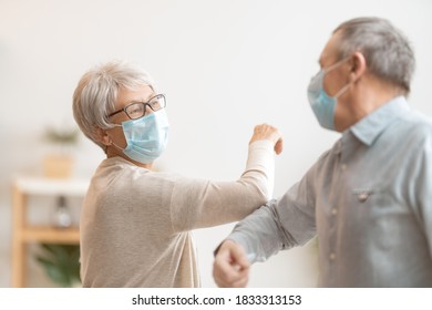 Senior couple wearing face masks and greeting bumping elbows during coronavirus and flu outbreak. Virus and illness protection, home quarantine. COVID-2019. - Powered by Shutterstock