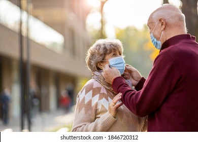 Senior Couple Wearing Protective Face Masks Outdoors 
