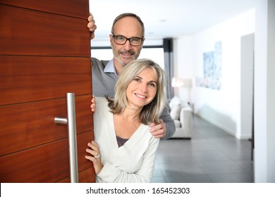 Senior Couple Welcoming People To Enter Home