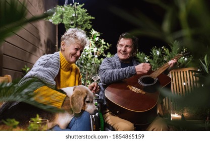 Senior couple in wheelchair with dog and guitar in the evening on terrace. - Powered by Shutterstock