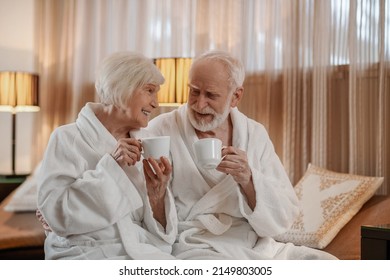 A senior couple in white robes having coffee and talking - Powered by Shutterstock