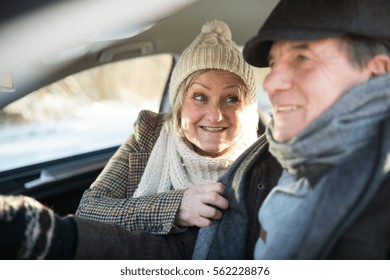 Senior Couple In Winter Clothes Driving A Car