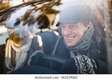 Senior couple in winter clothes driving a car