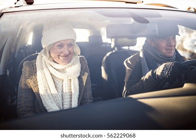 Senior Couple In Winter Clothes Driving A Car