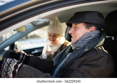 Senior Couple In Winter Clothes Driving A Car