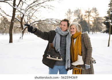 Senior Couple In Winter Nature With Ice Skates Going To Rink.