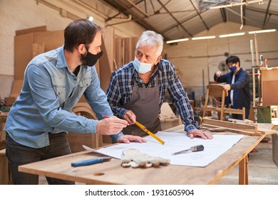 Senior Craftsman And Apprentice With Face Mask Because Of Covid-19 In The Workshop