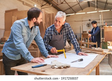 Senior craftsman and carpenter apprentice with a blueprint discuss a house building project - Powered by Shutterstock