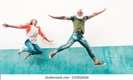 Senior Crazy Couple Jumping Outdoor - Mature People Having Fun Dancing And Celebrating Outside - Joyful Elderly Lifestyle Concept - Focus On Faces