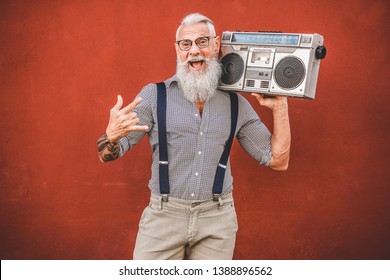 Senior crazy man with boombox stereo playing rock music - Trendy mature guy having fun dancing with vintage radio - Joyful elderly lifestyle concept - Focus on his face