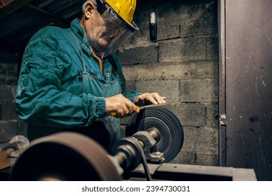 A senior cutler is sharpening knife on whetstone in his workshop. - Powered by Shutterstock