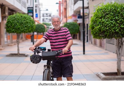 Senior cyclist man pushing his electric bicycle in urban street. Active elderly handsome pensioner enjoying a healthy lifestyle and freedom - Powered by Shutterstock