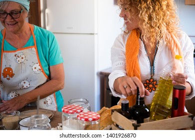 Senior And Daughter Cooking Together At Home- Grandma Showing And Teach How To Cook Fish - Have Fun And Happy Moment Indoor- Eating At The Kitchen - Mature Woman With Glasses And Retired 60s Caucasian