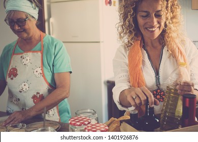 Senior And Daughter Cooking Together At Home- Grandma Showing And Teach How To Cook Fish - Have Fun And Happy Moment Indoor- Eating At The Kitchen - Mature Woman With Glasses And Retired 60s Caucasian