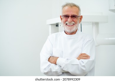 Senior dentist man stand with arm-crossed or confident in front of dental x-ray machine. - Powered by Shutterstock