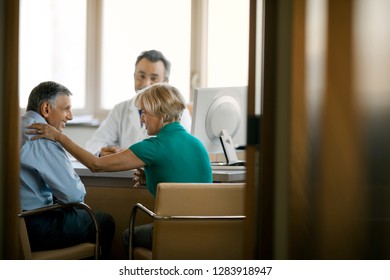 Senior doctor consulting with patients in his office.