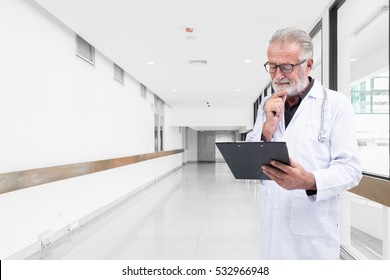 Senior Doctor Was Examine A Medical Record In The Hospital Hallway